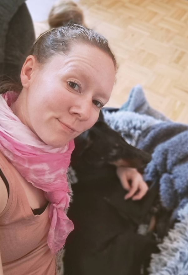 Melanie Tso und Manchester Terrier Monty Eine Person mit lila Kopfbedeckung und ein Hund posieren zusammen.